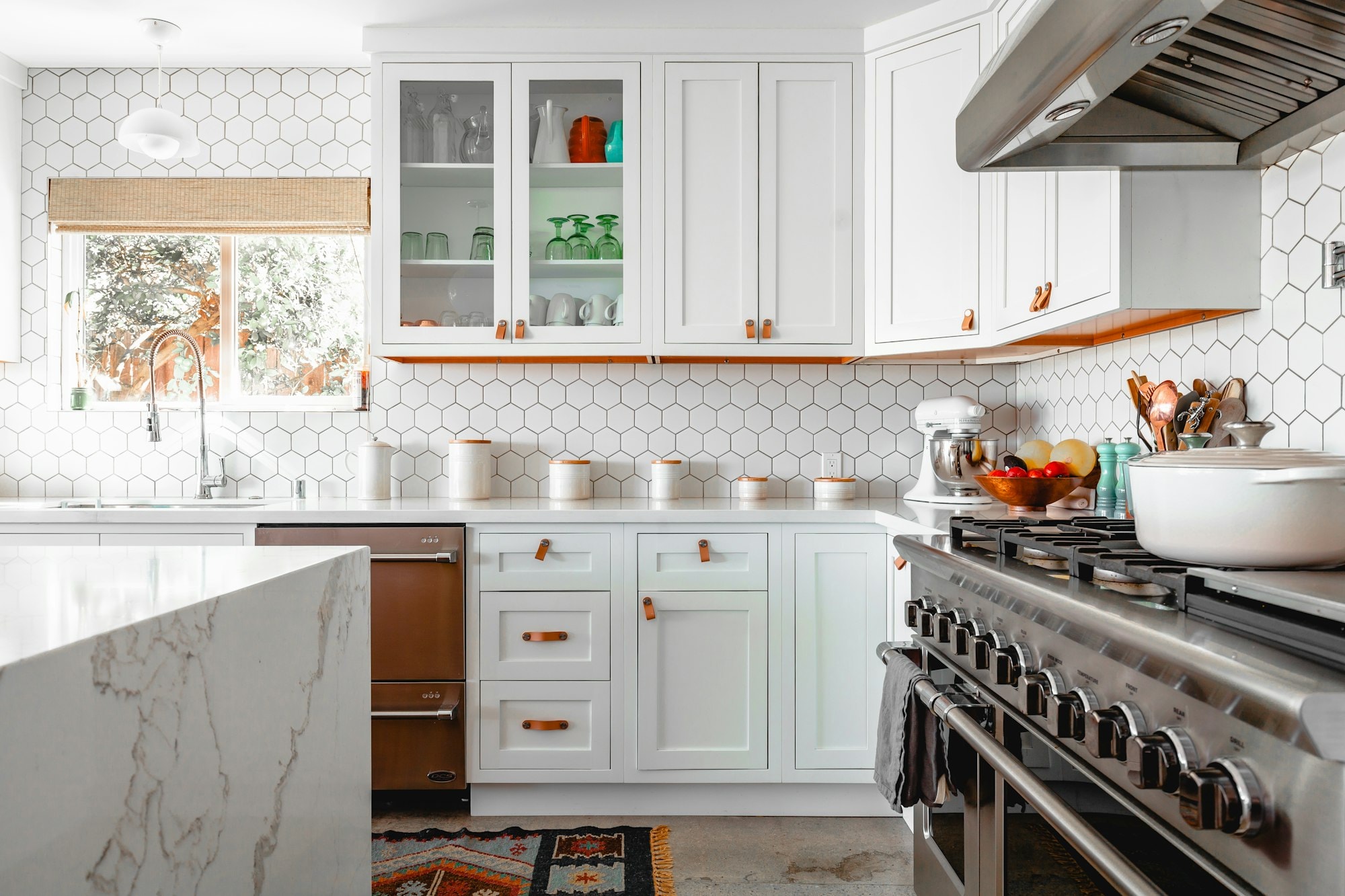 Bright kitchen with white cabinets, hexagon tile and a marble island